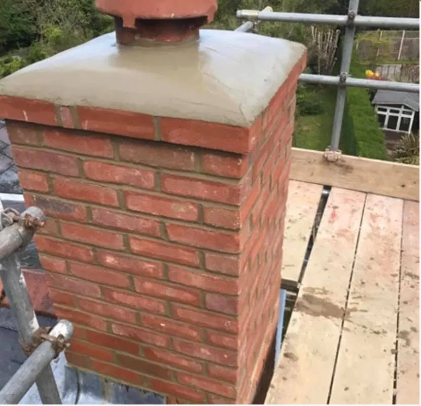 Brick chimney stack rebuilt with a new rendered cap, seen from the scaffold