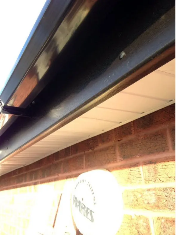 Black UPVC gutter and fascia with white soffit above a brick wall