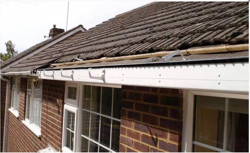 New white UPVC fascia boards being fitted along the eaves of a brick bungalow