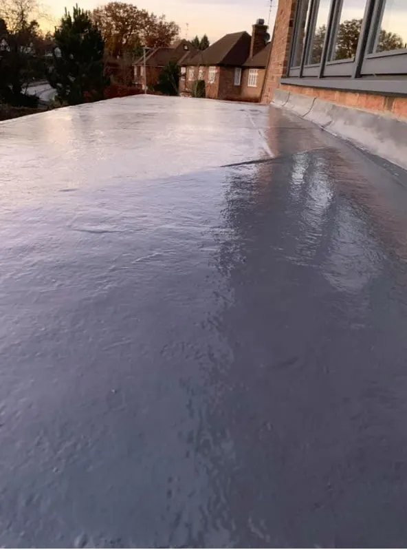 Glossy grey GRP fibreglass flat roof with the house wall alongside