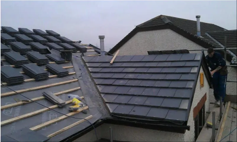 Slate roof part way through re-roofing, slates stacked on the battens beside the finished hip