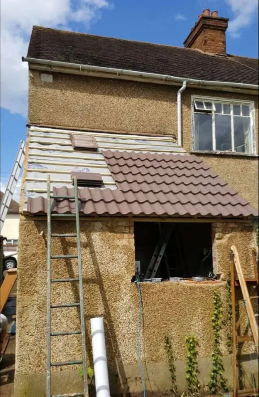 New tiled roof on a two-storey rear extension with scaffold and ladder against the wall